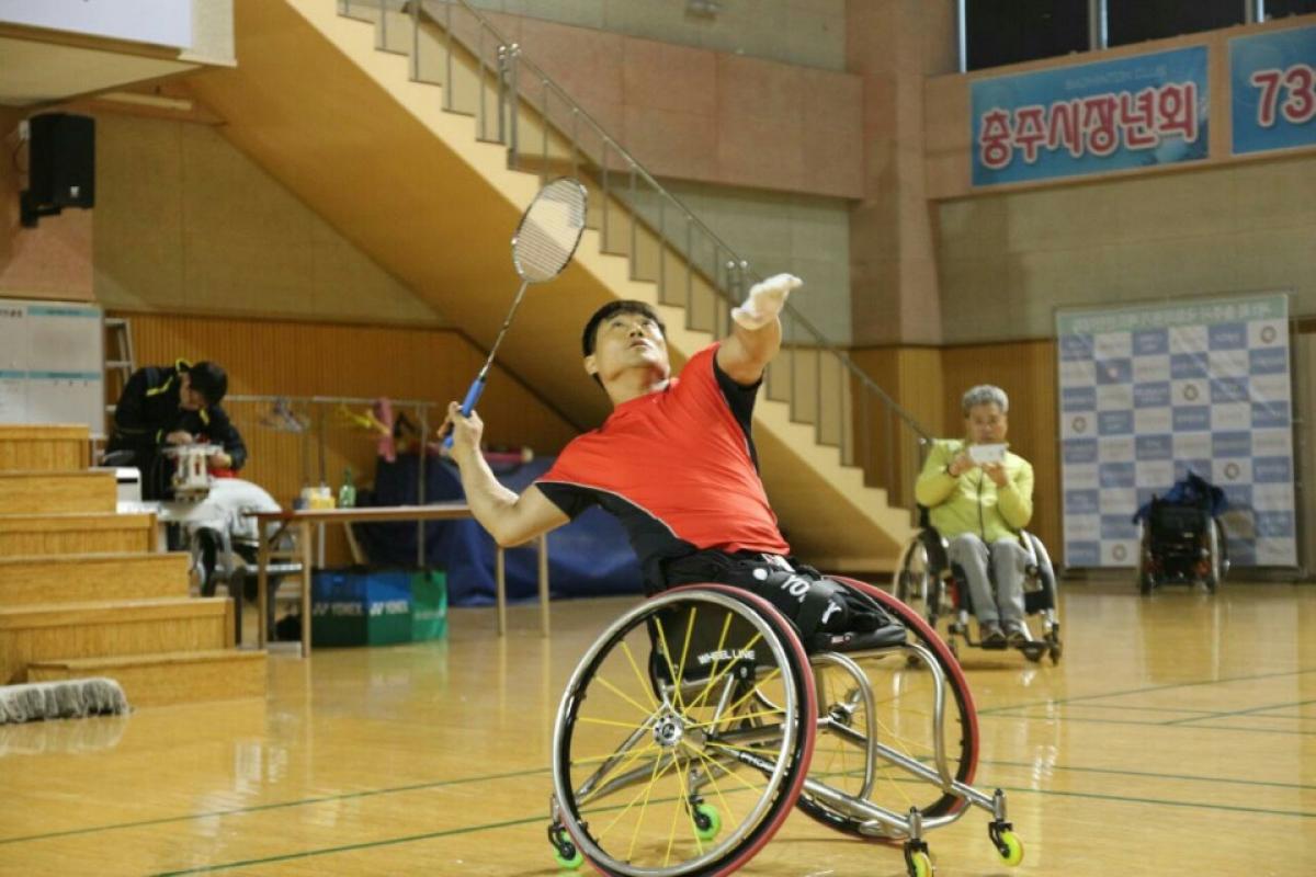 a para badminton player in a wheelchair goes for a shot