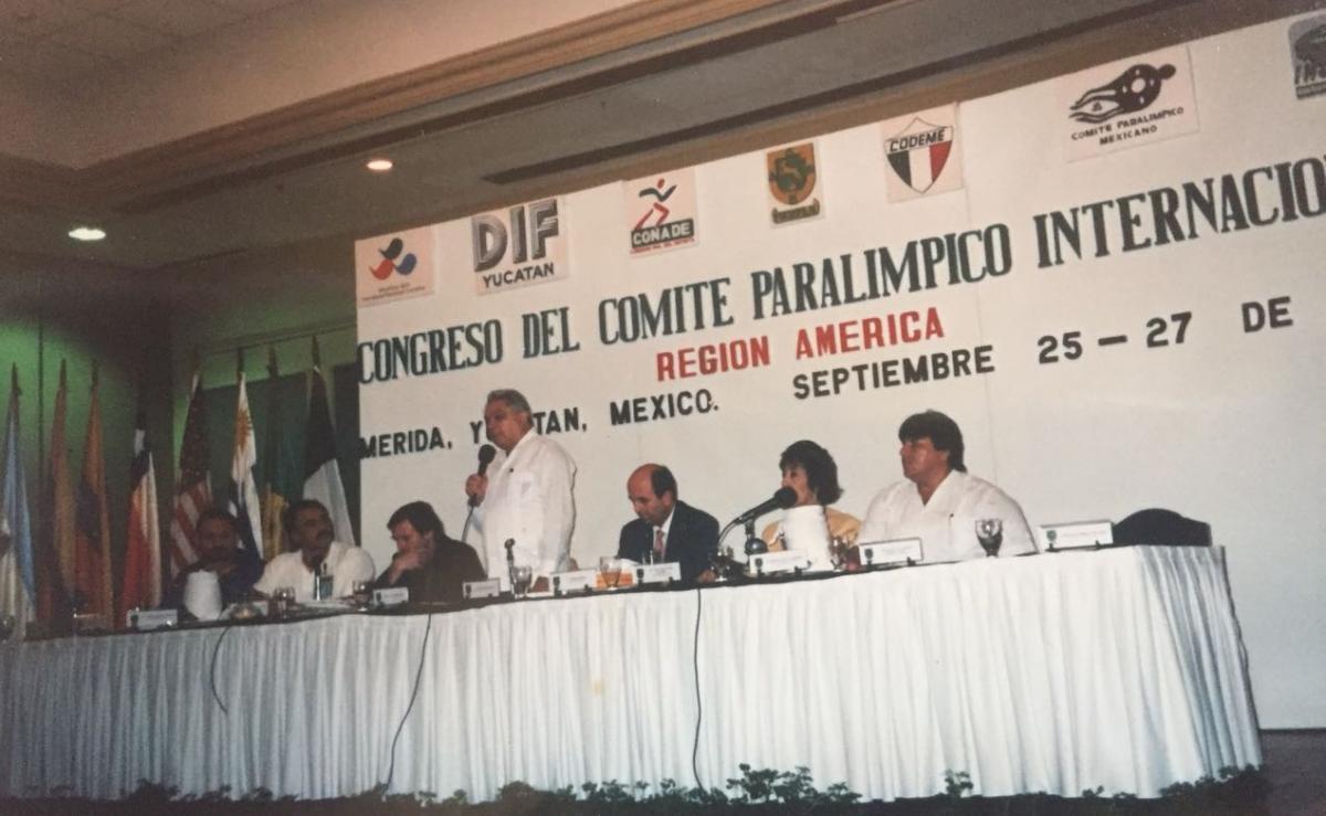 a group of men speak at a table