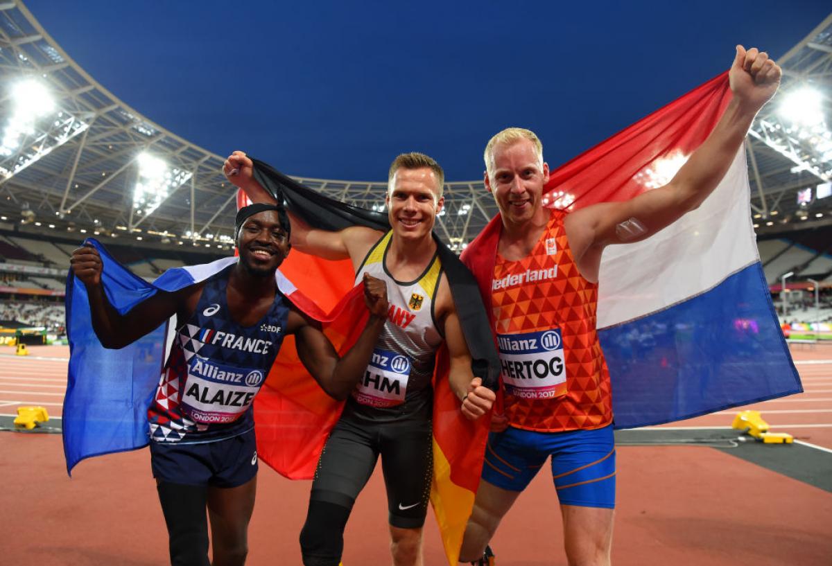 three men celebrate with the flags of their countries