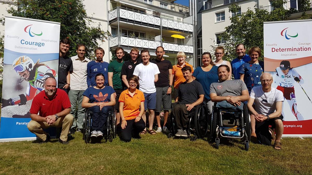 a group of officials and Para athletes smile for the camera