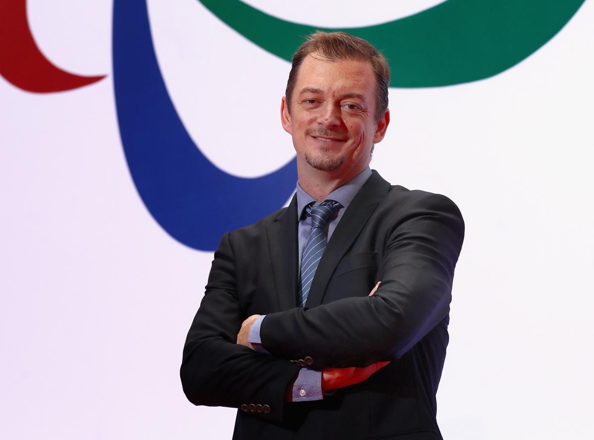 A man standing in front of the Agitos symbol