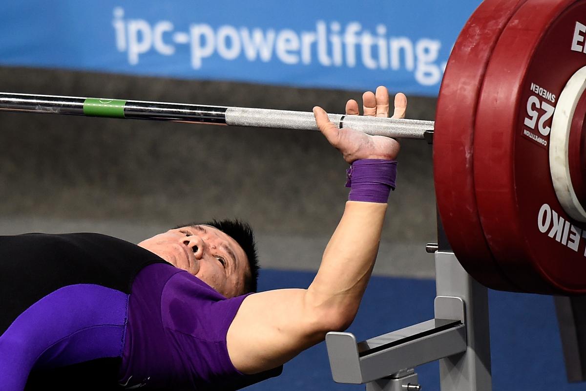 Man lays on bench preparing to bench press. 