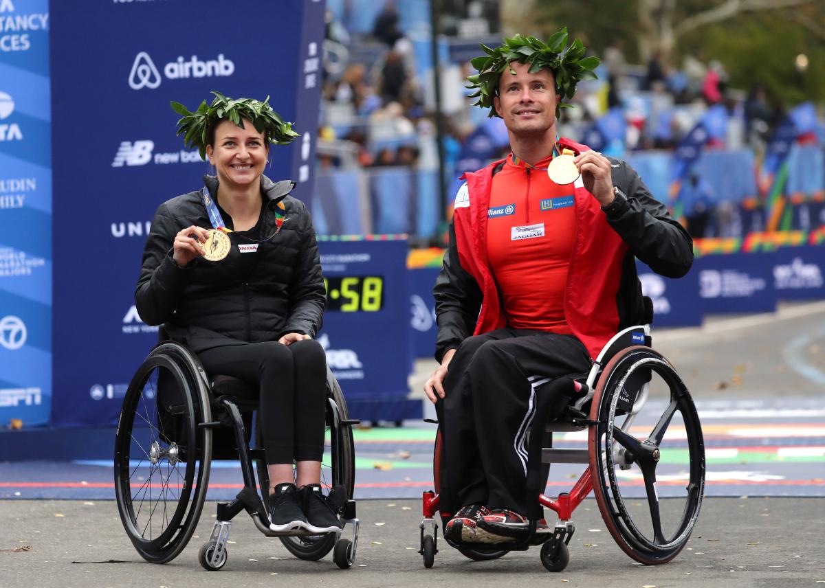 a male and female wheelchair racer celebrate with their gold medals