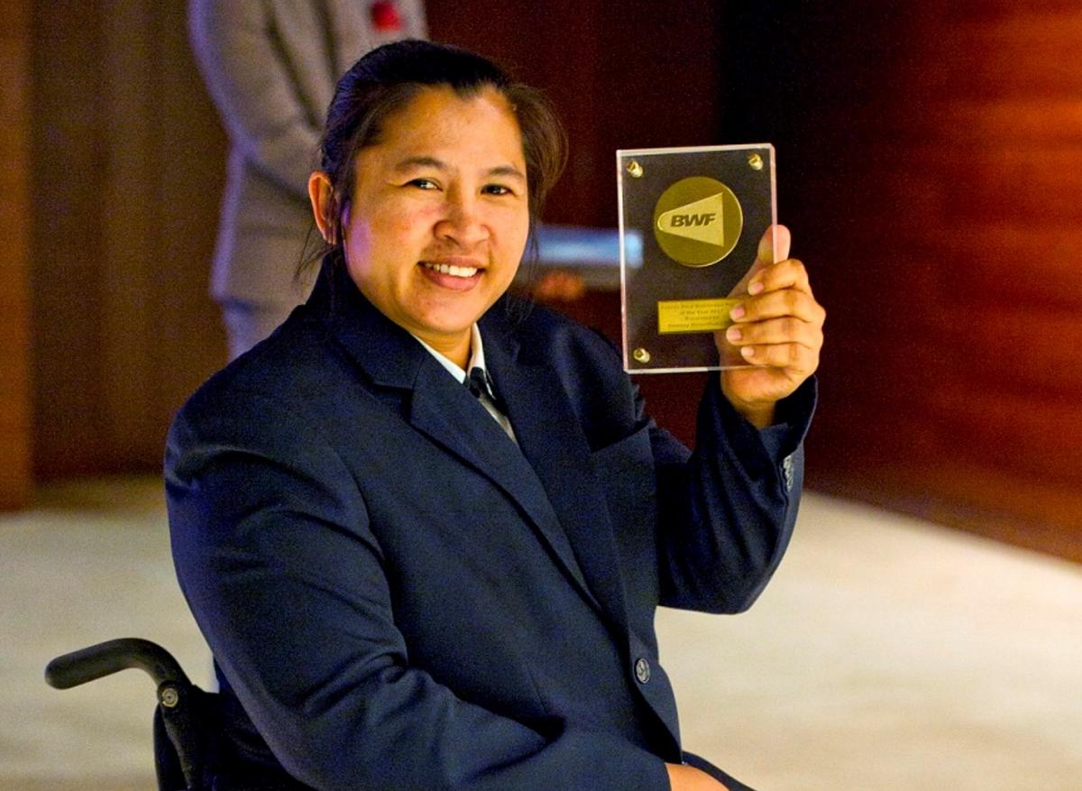 a female Para badminton player holds up an award