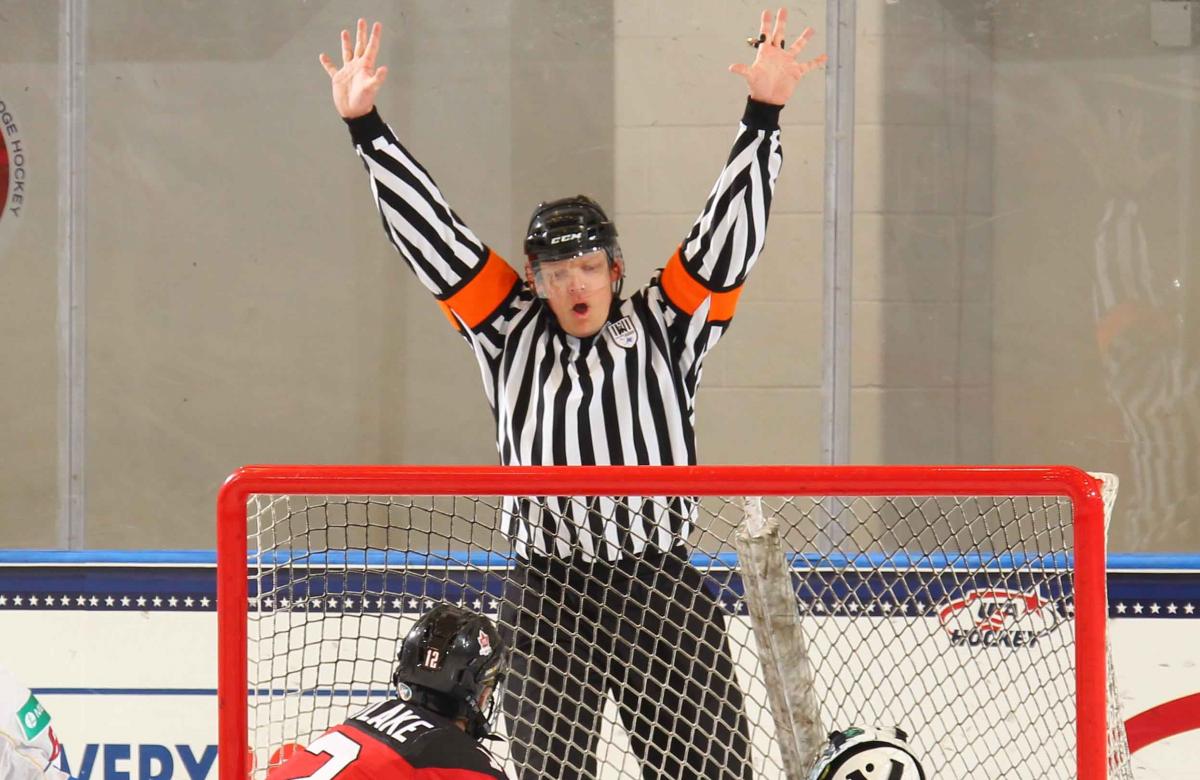 a male Para ice hockey referee throws his hands up to signal