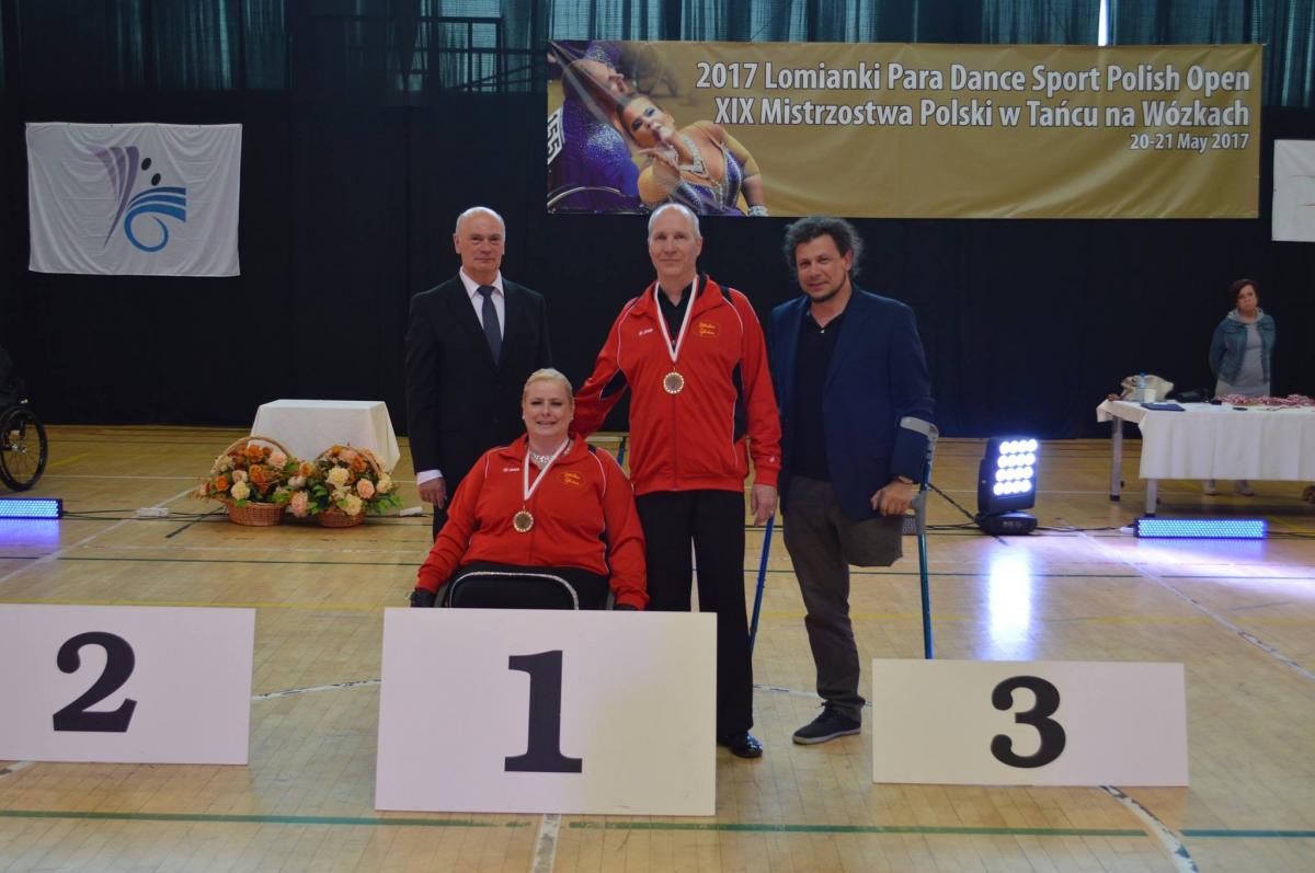 Female dancer in wheelchair poses for photo with standing partner and two other officials