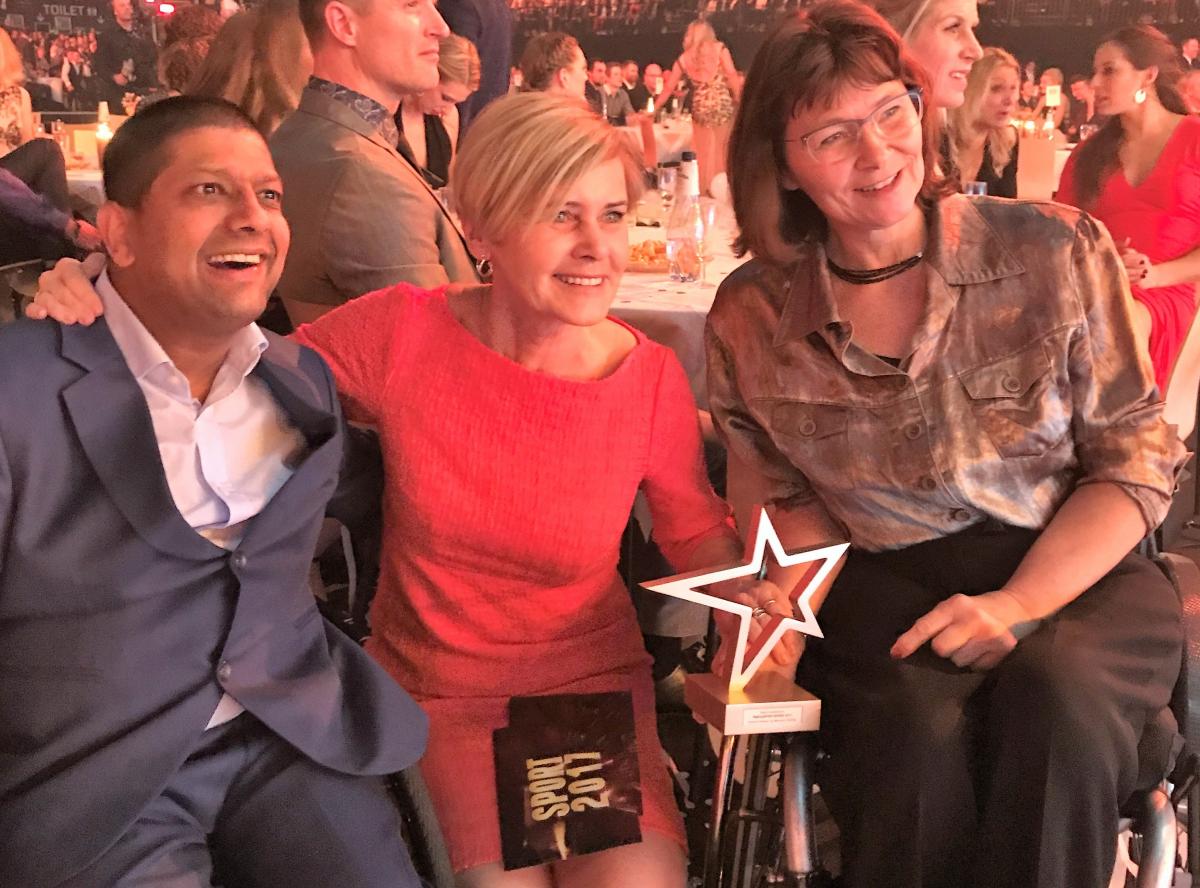 a man and two women smiling with a trophy