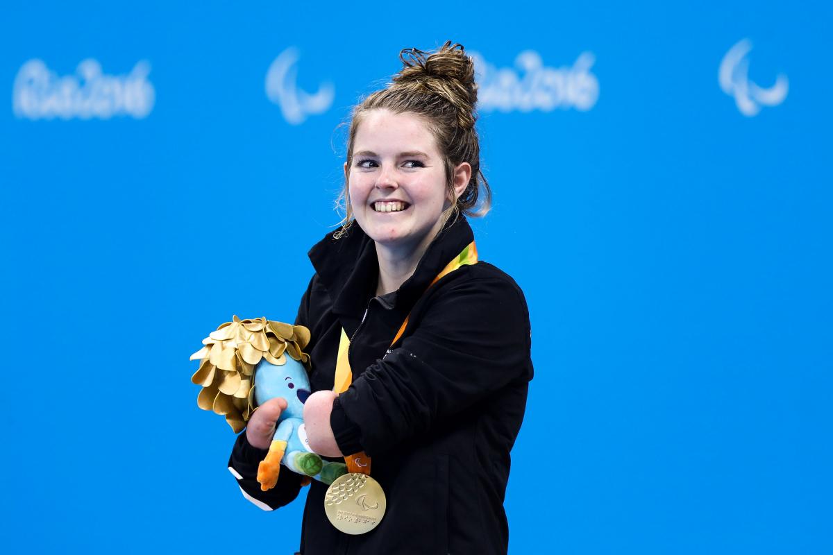 a Para swimmer smiles with her gold medal on the podium