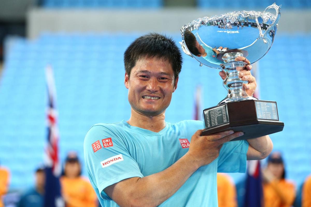 Man smiling and lifting a silver trophy