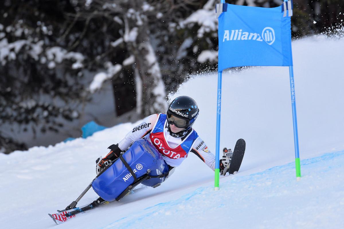 a female sit skier rounds a gate