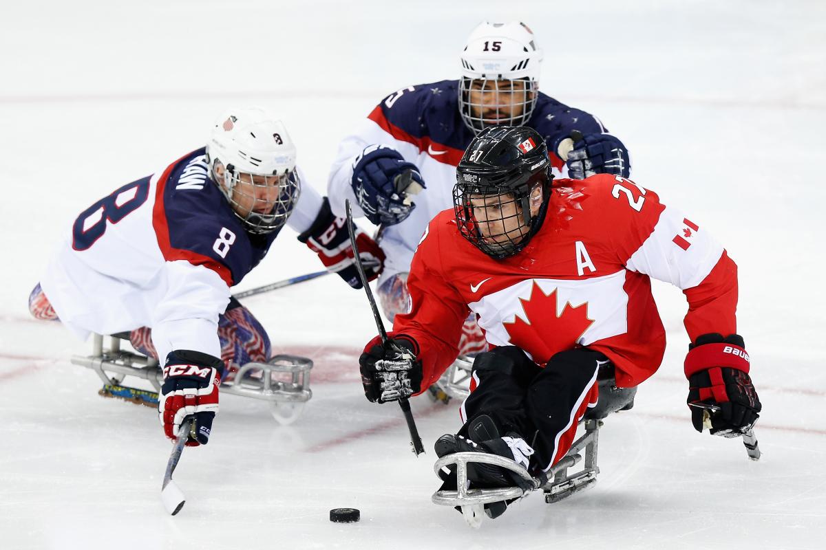 three male Para ice hockey players clash on the ice