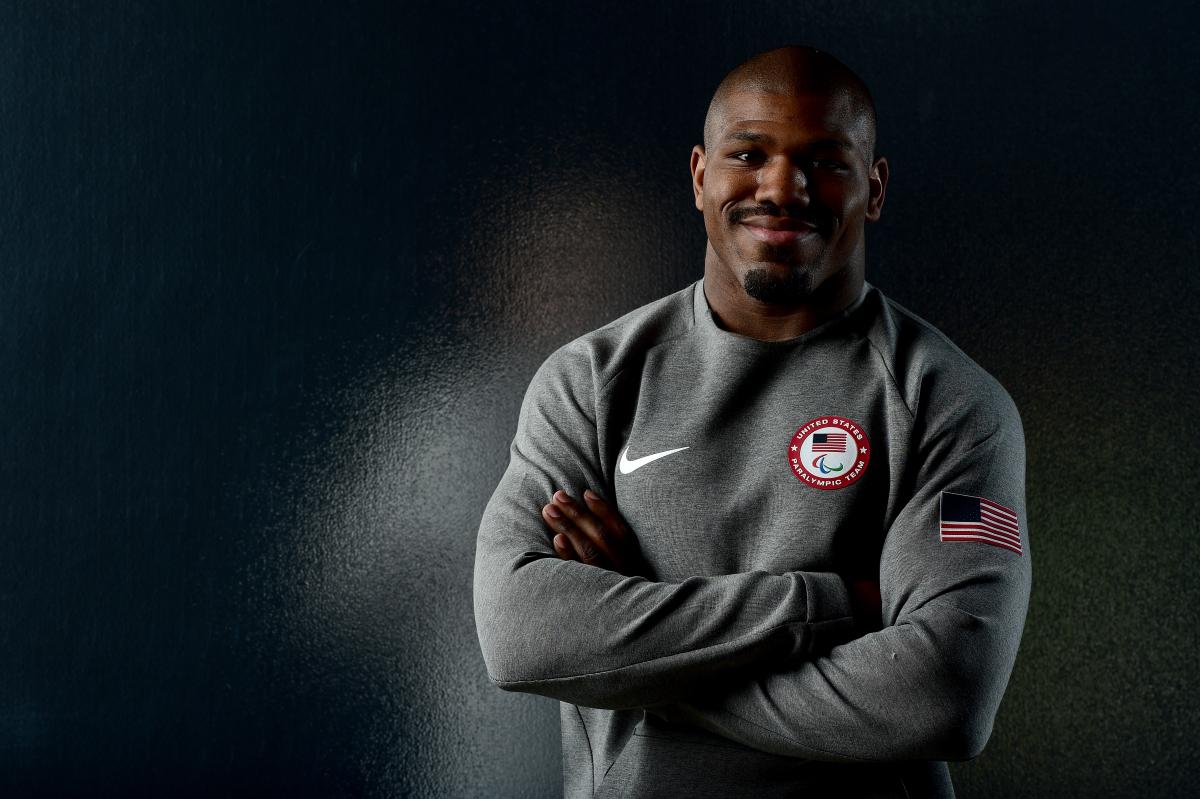 a male judoka smiles with his arms folded