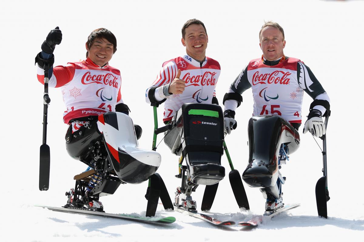 three male sit skiers celebrating on the snow 