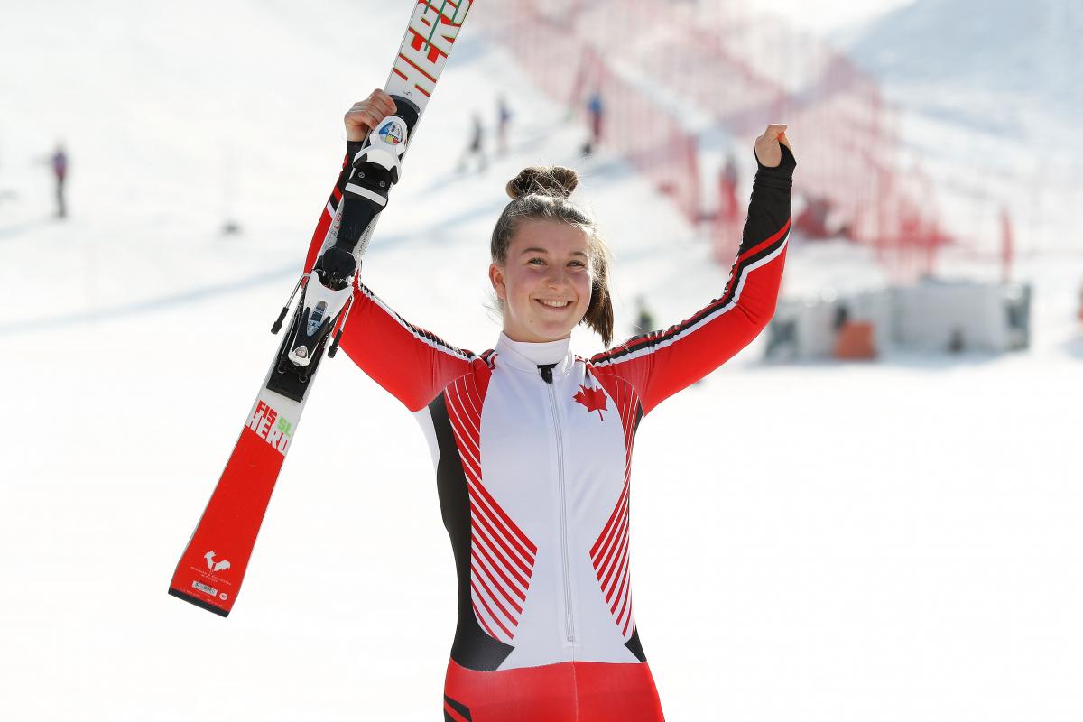 a female Para skier raises her arms in celebration