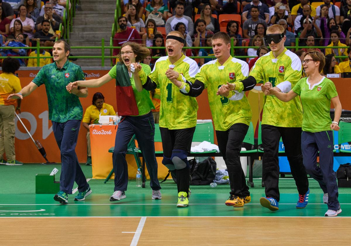 a group of goalball players link arms in celebration