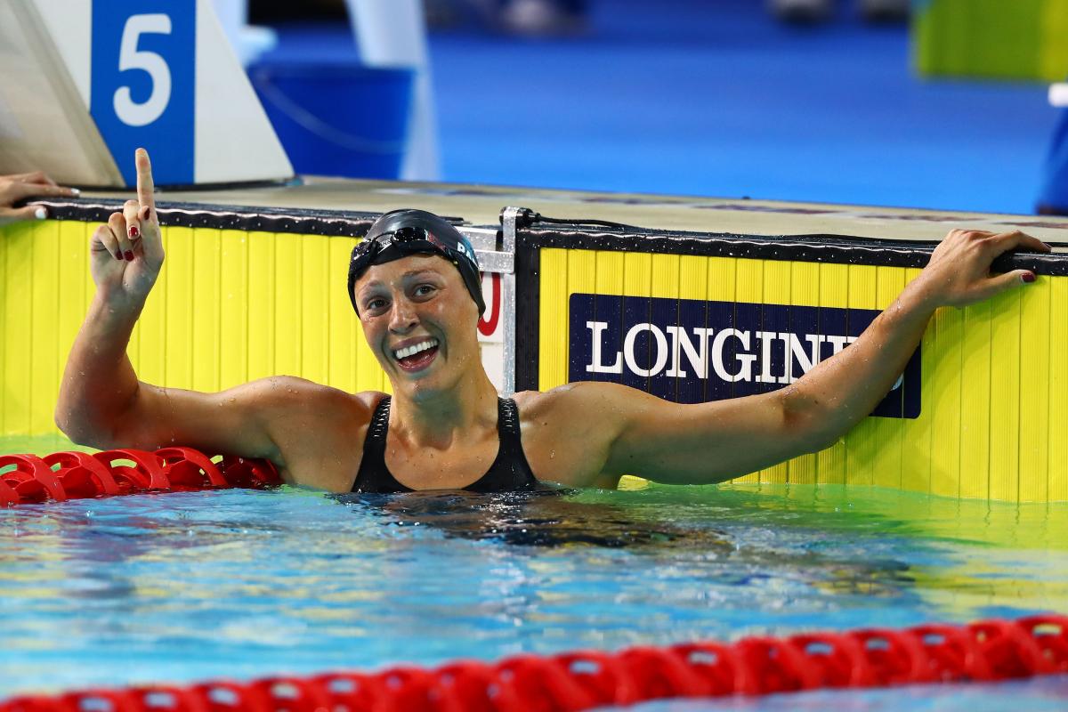 a female swimmer raises her arm in celebration in the pool