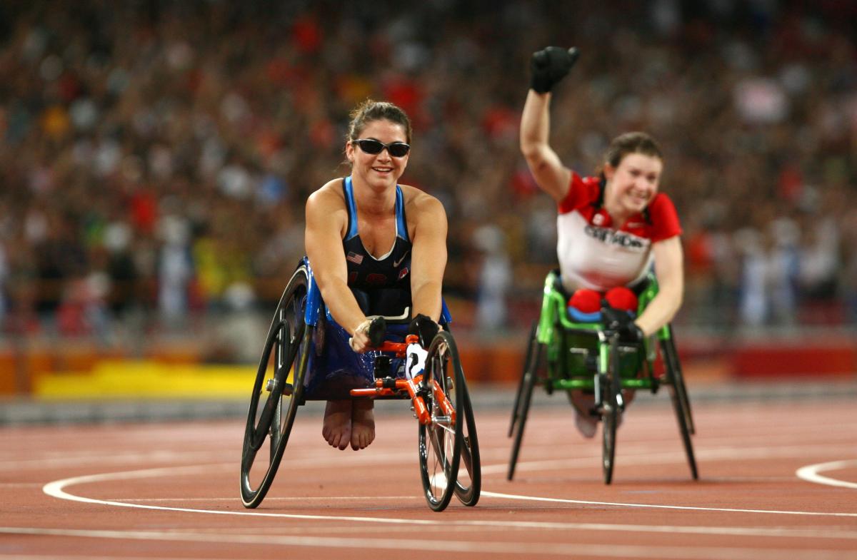 a female wheelchair racer celebrates after the finish line