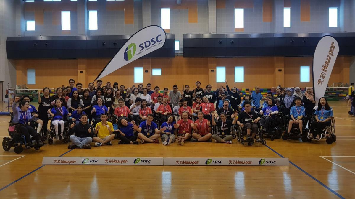 a group of boccia players and children sitting in a gym