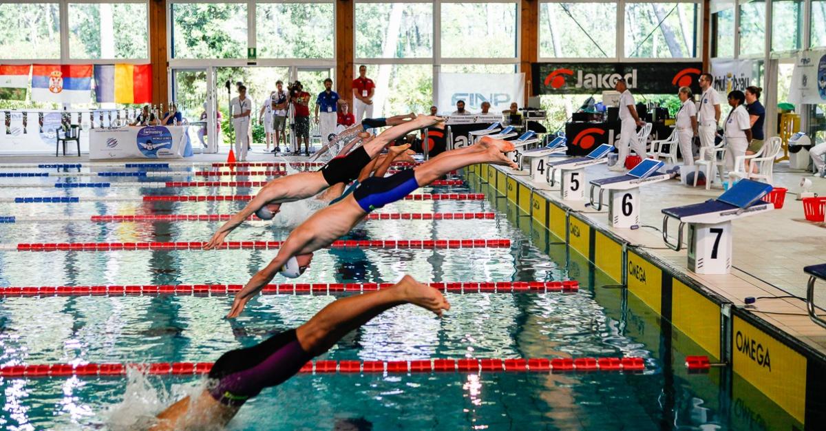 a group of Para swimmers dive into the pool at the start of the race