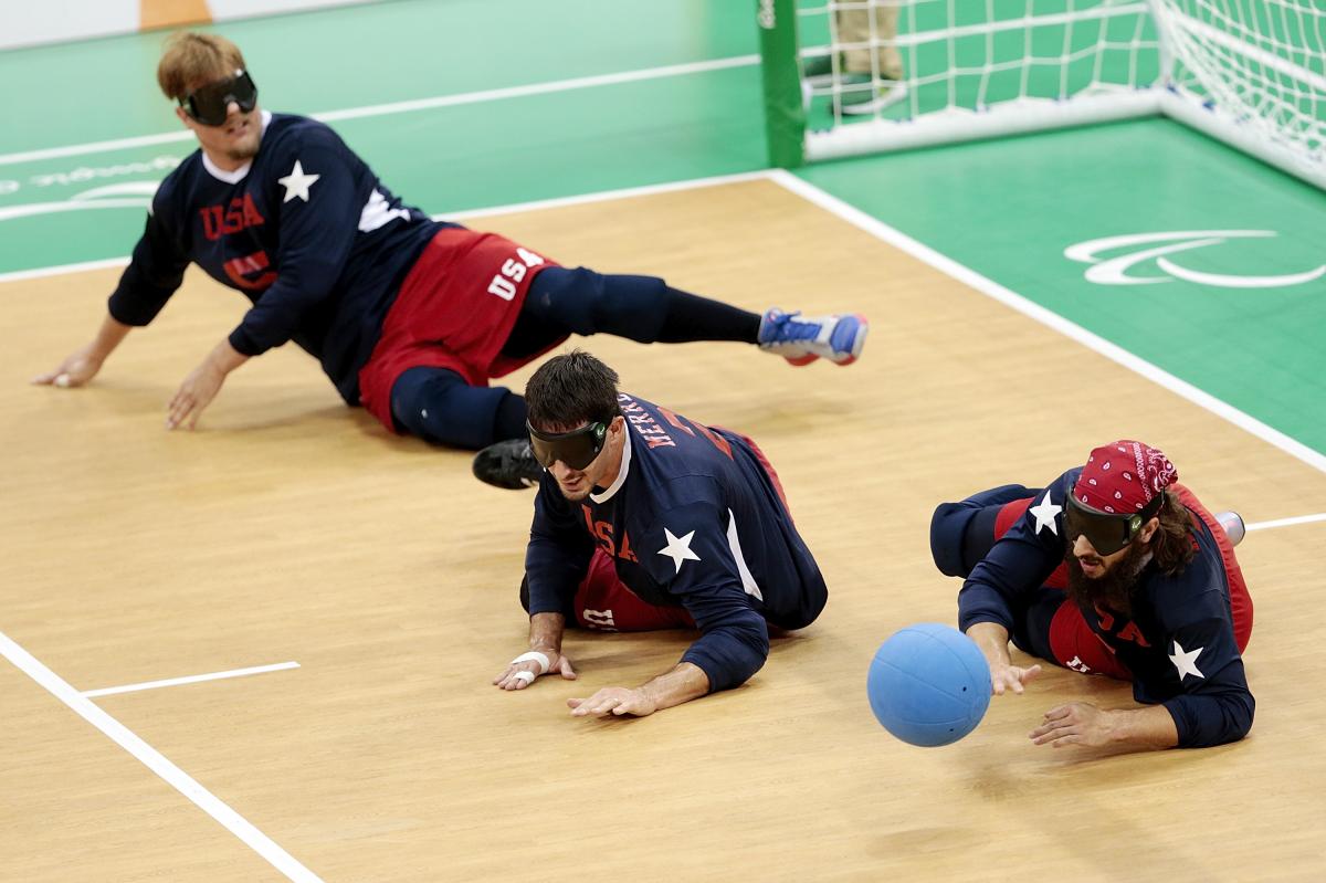 a male and female goalball player dive to save a shot