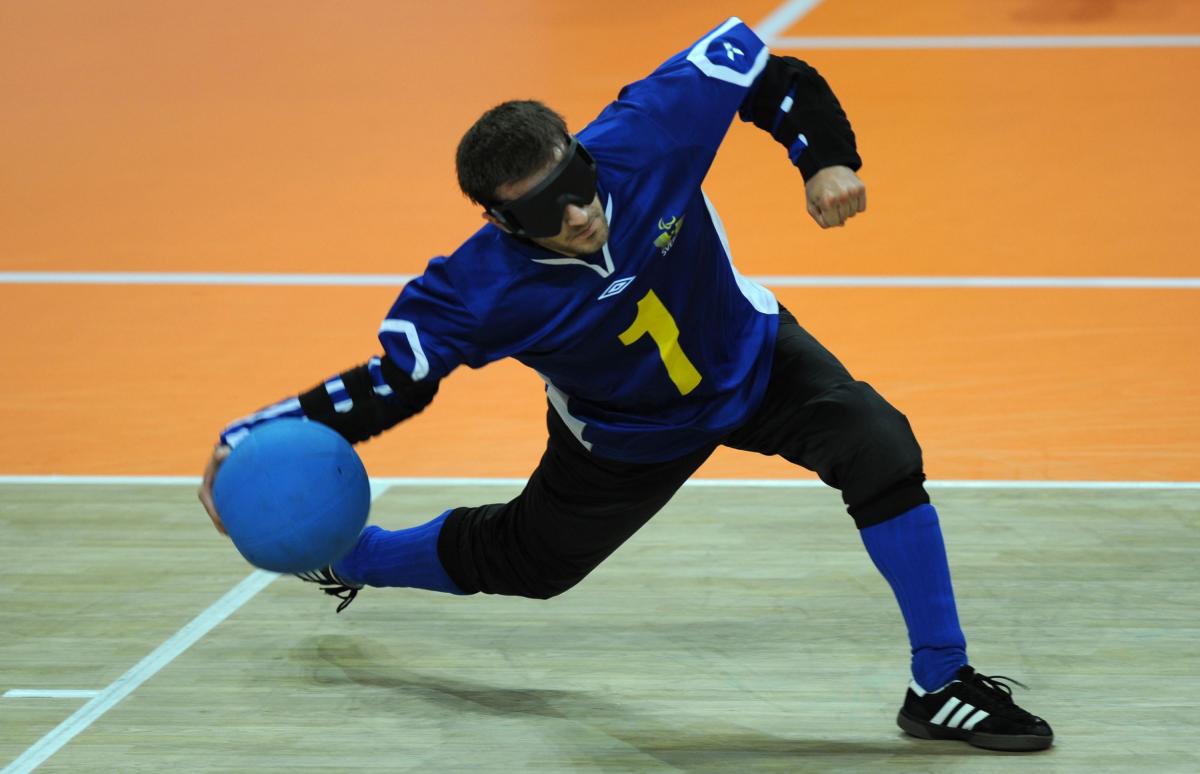 a male goalball player prepares to throw the ball