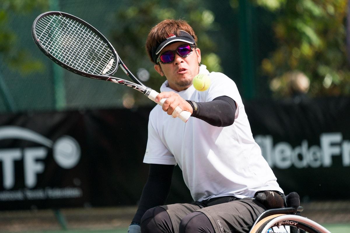 a male wheelchair tennis player goes for a backhand shot