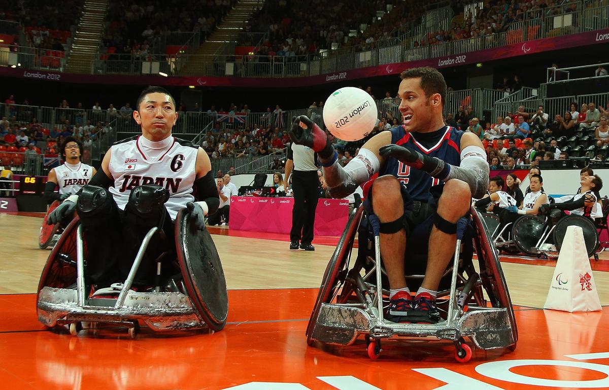 two male wheelchair rugby players with one holding a ball 