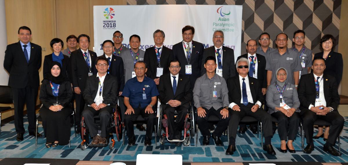 a group of men and women in a boardroom smiling at the camera