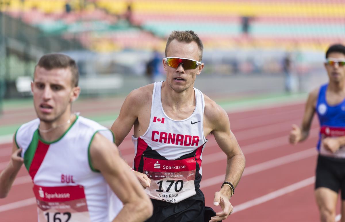 a male Para athlete overtakes another runner on the track