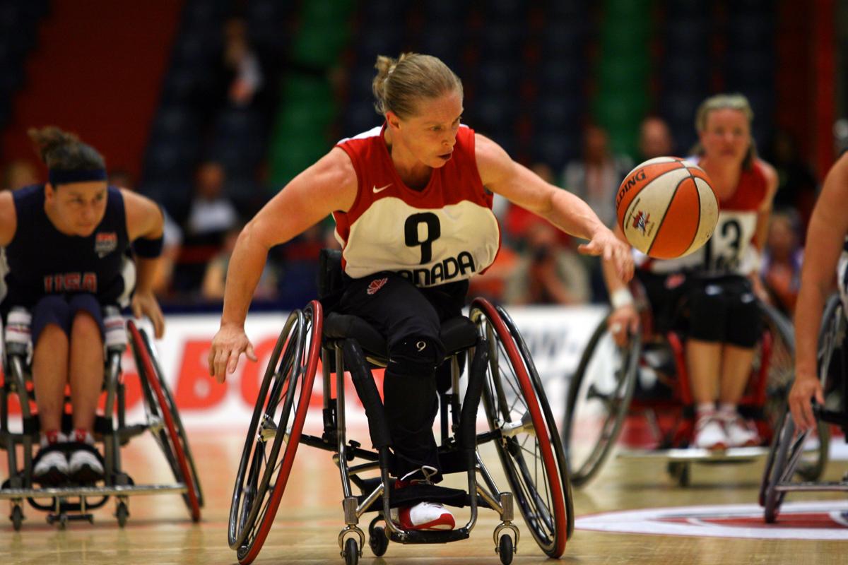 a female wheelchair basketballer dribbles the ball