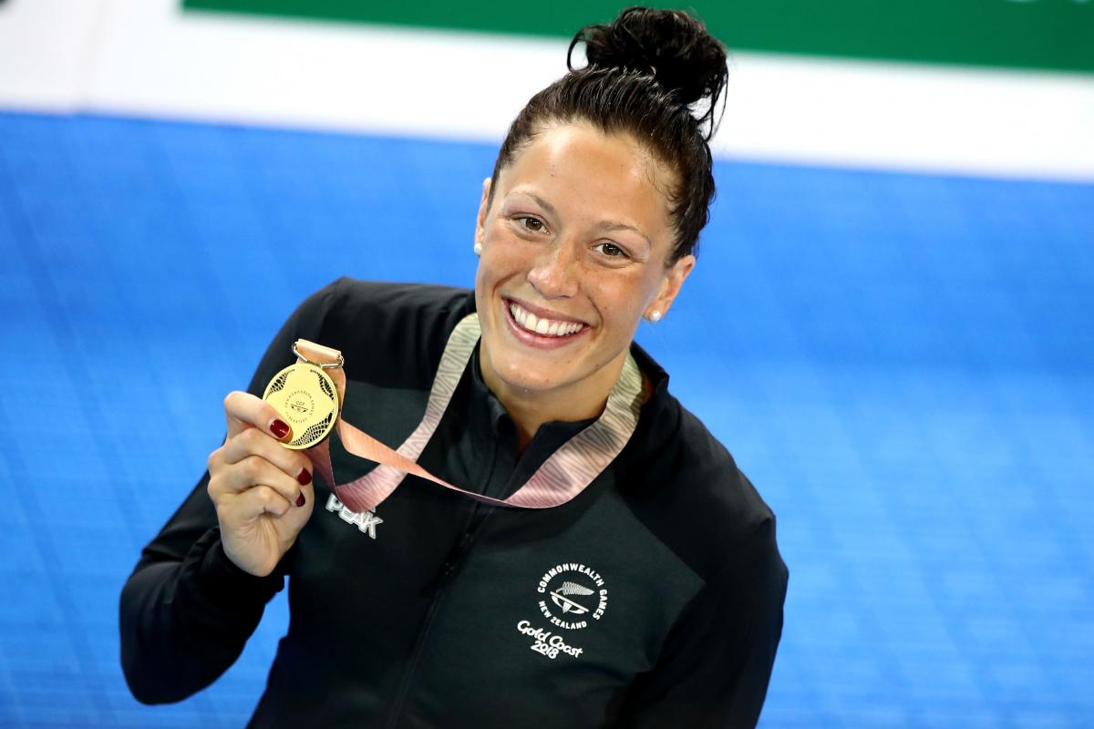 female Para swimmer Sophie Pascoe holds up a gold medal by the pool