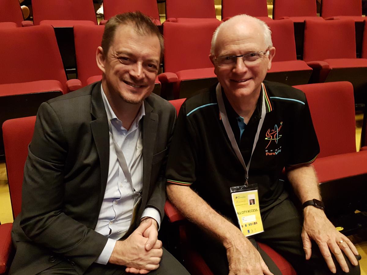 two men, Andrew Parsons and Barry Couzner, smiling and shaking hands