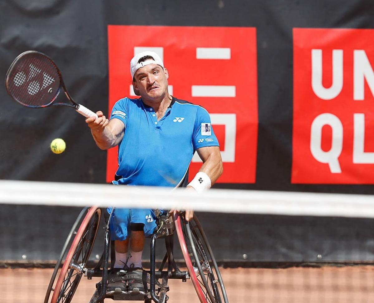 male wheelchair tennis player Gustavo Fernandez plays a forehand on a clay court