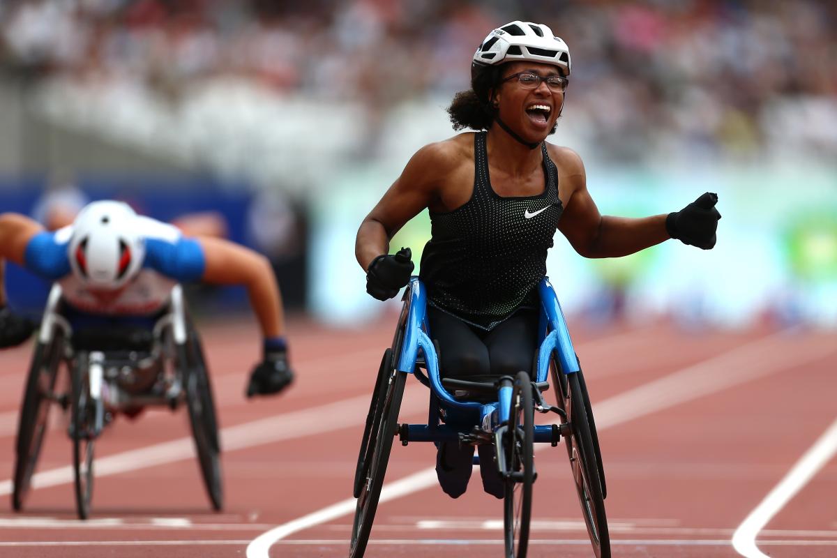 female wheelchair racer Kare Adenegan celebrates as she crosses the finish line