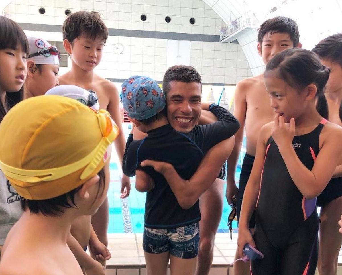 A man hugging a child in the middle of a group of children