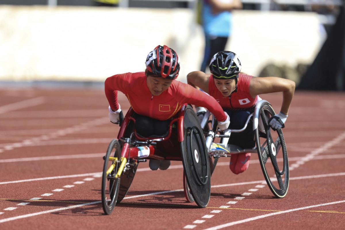 female wheelchair racer Hongzhuan Zhou rolls her wheels to stay ahead of a Japanese athlete