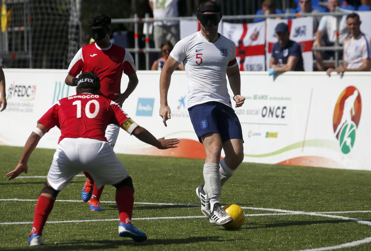 male blind footballer Dan English dribbles the ball past an opposition player