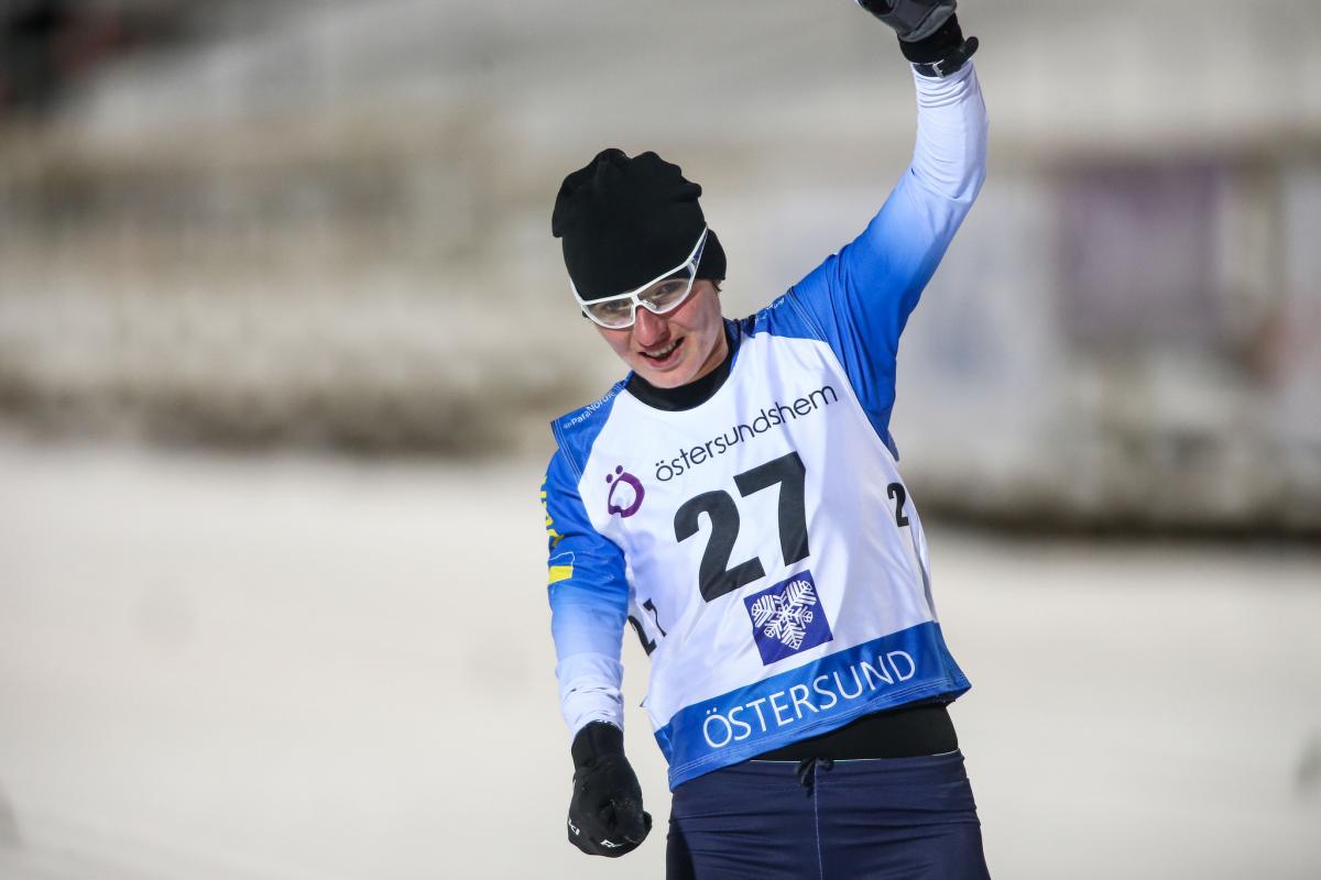 female Para biahthlete Oleksandra Kononova raises her fist in triumph as she crosses the finish line