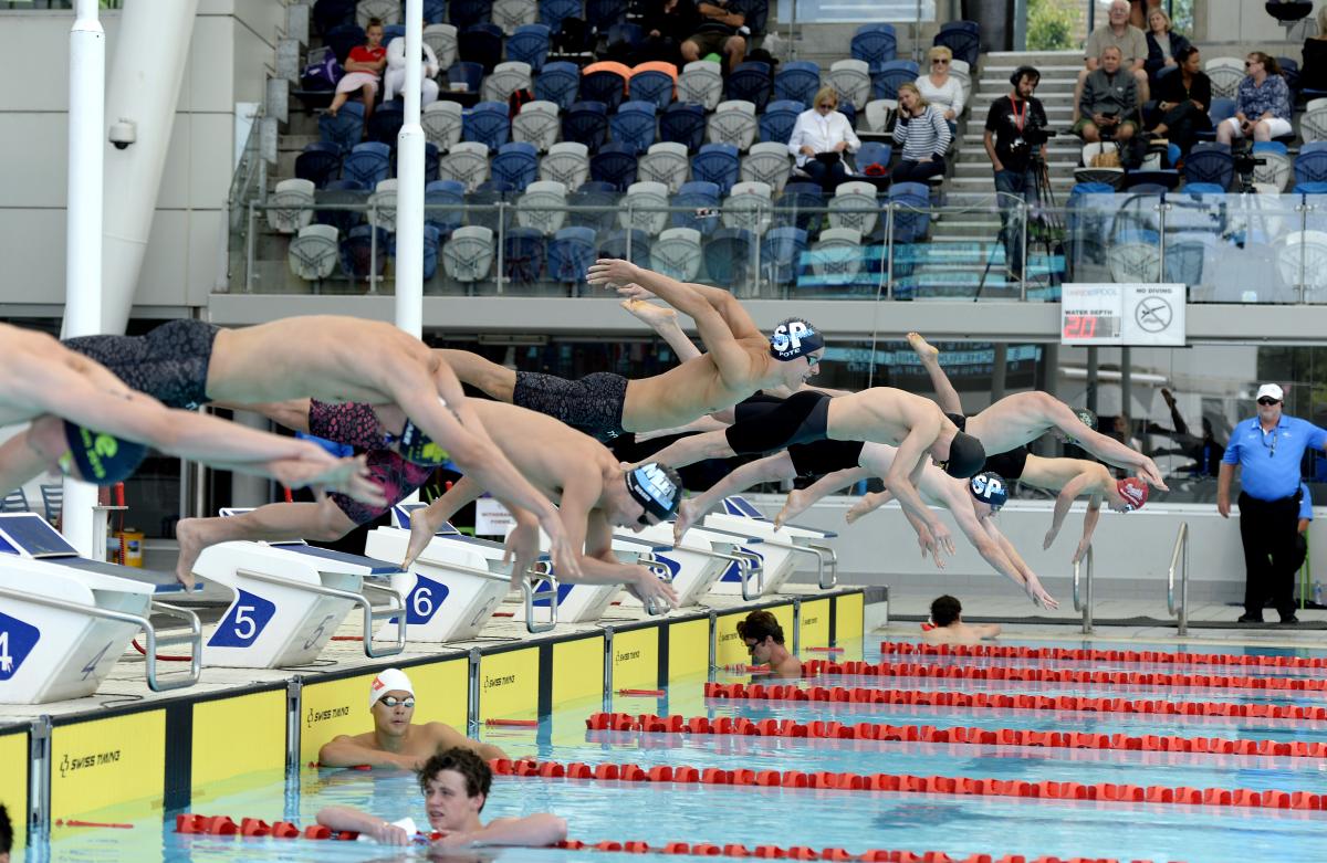 male Para swimmers diving into a pool at the start of the race in Melbourne