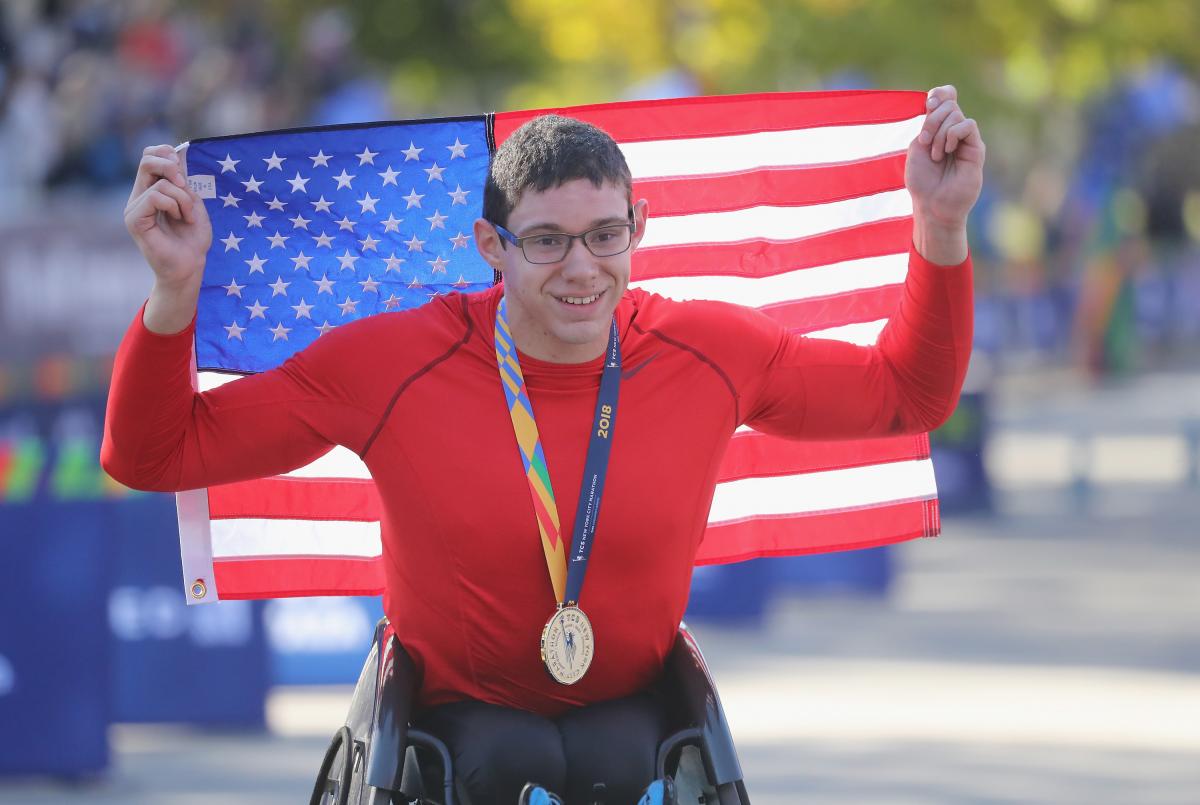 male wheelchair racer Daniel Romanchuk holding up a USA flag