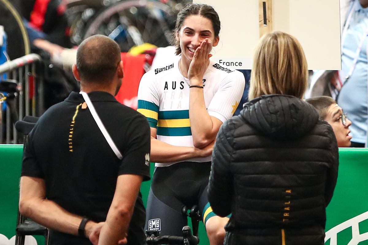 female Para cyclist Paige Greco smiles at two team officials