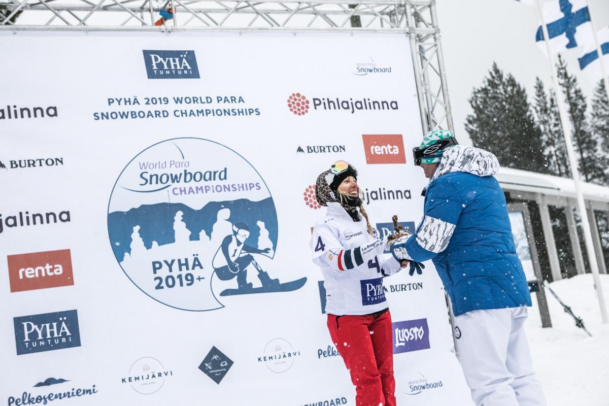 female Para snowboader Cecile Hernandez accepts her gold medal on the podium