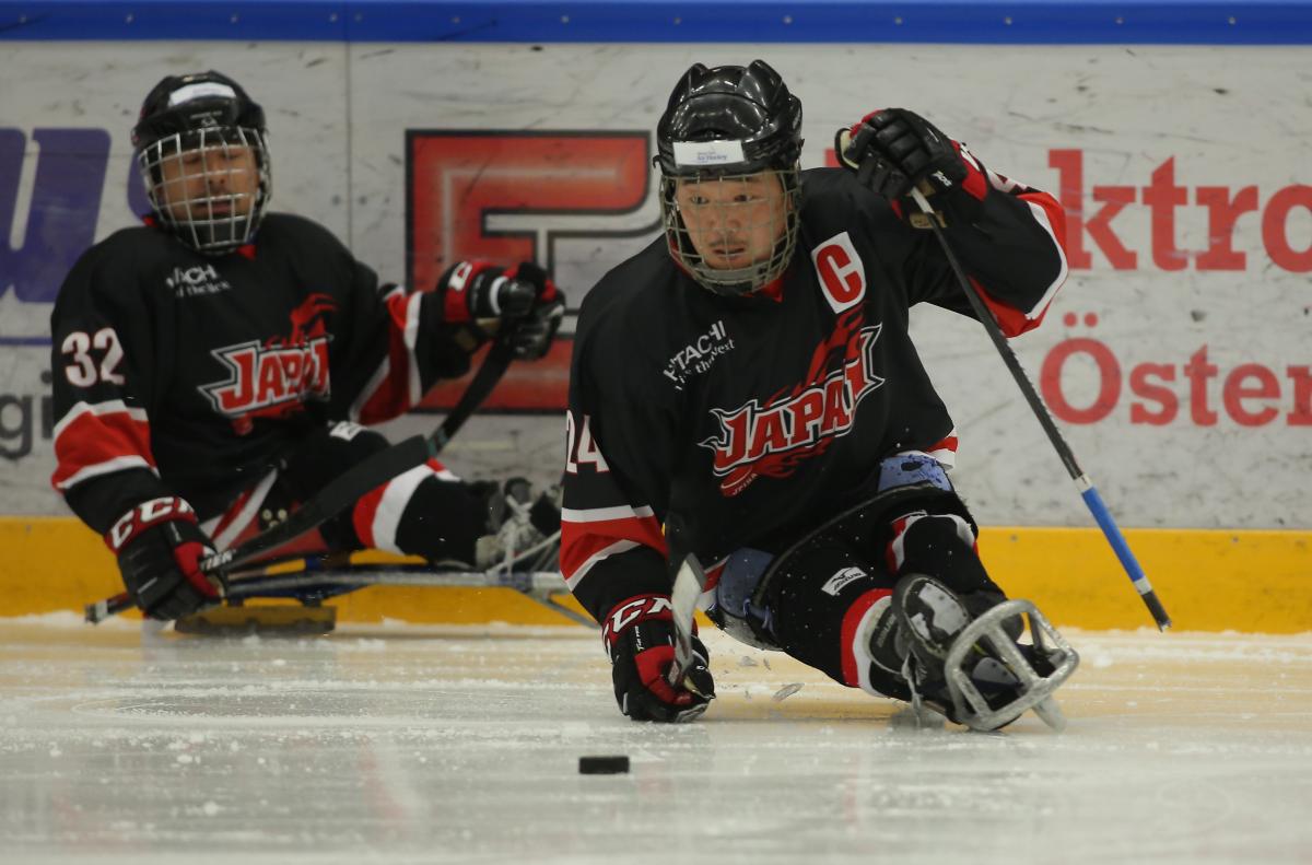 Japanese male Para ice hockey player skates with the puck