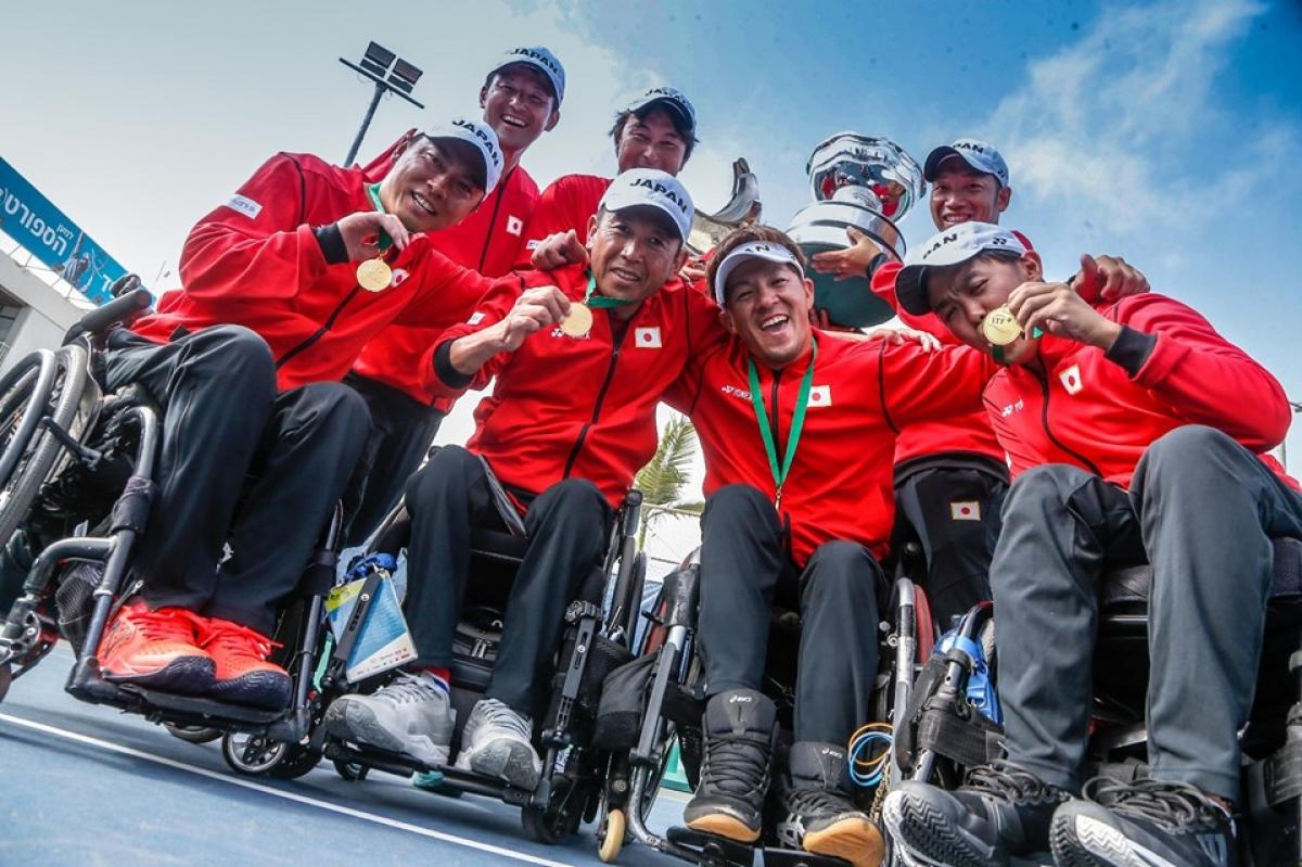 Japanese quad team smile and show their gold medal to the camera