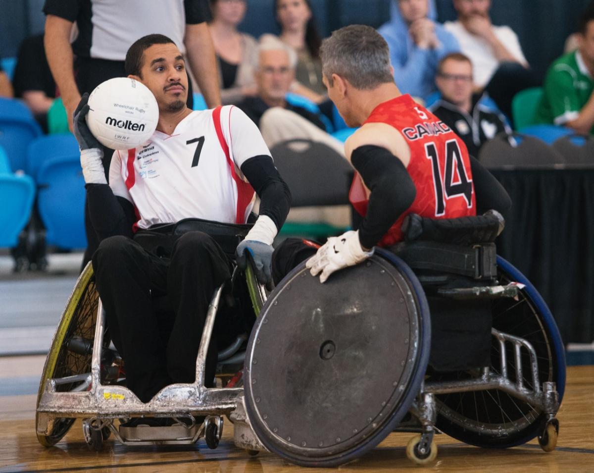 Swiss man in wheelchair rugby protects the ball against his opponent