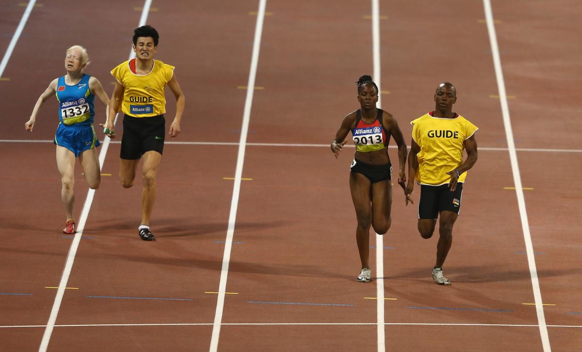 Two female vision impaired sprinters racing with their guides