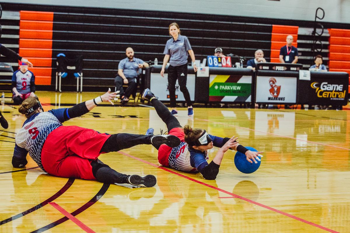 A female goalballer slides to block the ball from entering the goal